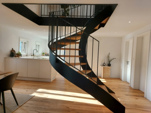 Escalier bois et métal, demi tournant avec limons métallique cintrés, garde-corps à barreaudage et marches en chêne massif